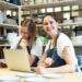 two smiling female entrepreneur with laptop in artisan workroom